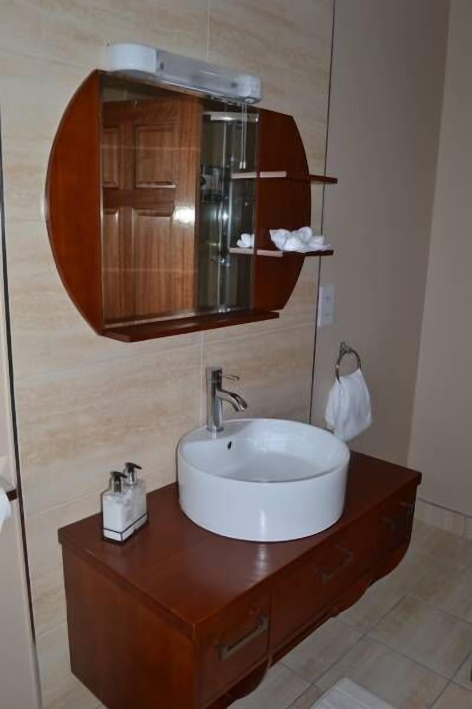 A bathroom with a round sink, a mirror above it, and a wooden vanity.