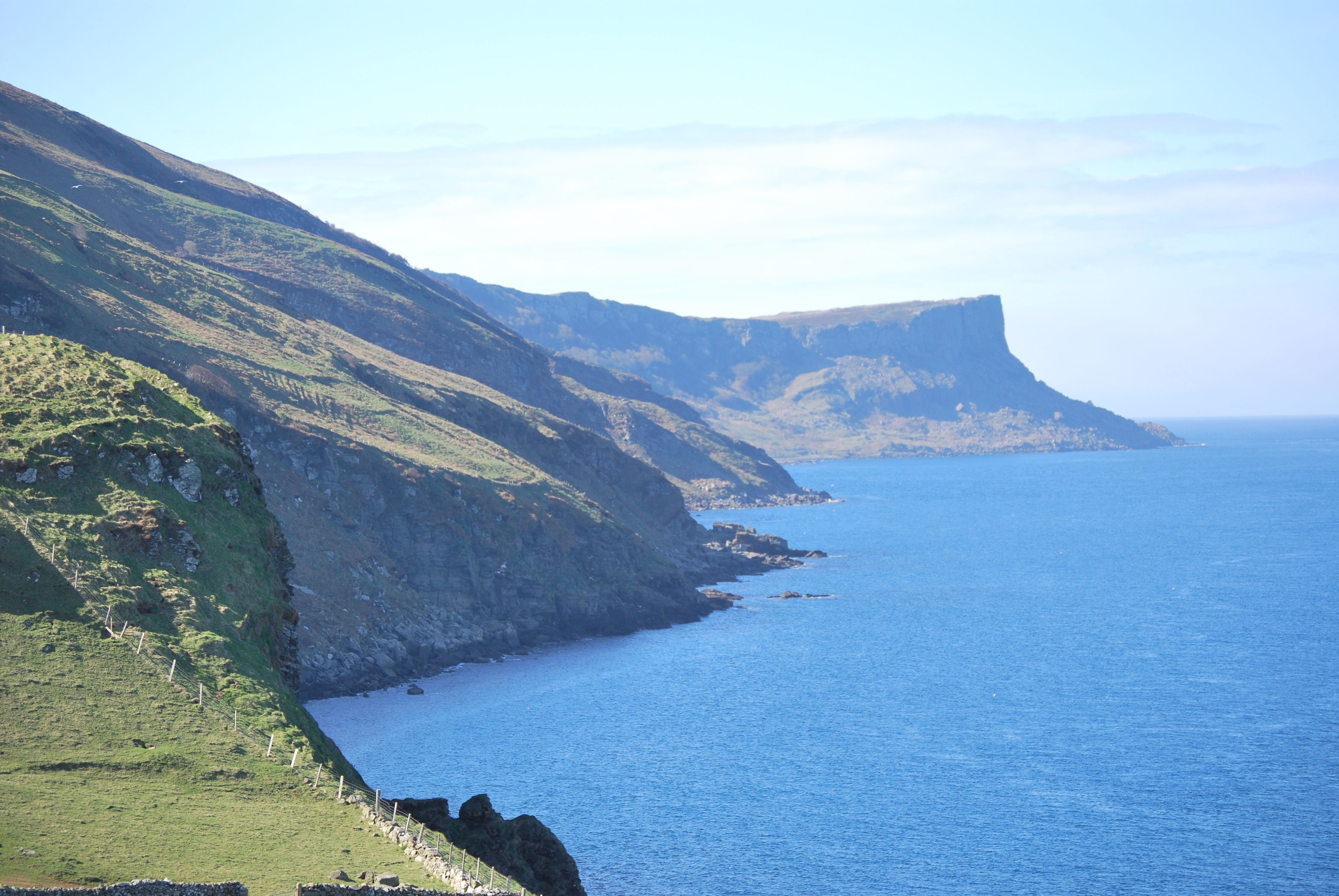 A coastal landscape with steep cliffs and a calm sea.