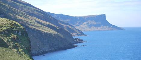 A coastal landscape with steep cliffs and a calm sea.