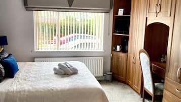 Ein Schlafzimmer mit zwei Betten, einem Holzschrank, einem Heizkörper und einem Fenster mit Jalousien.
