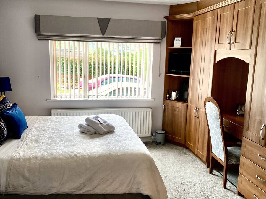 Ein Schlafzimmer mit zwei Betten, einem Holzschrank, einem Heizkörper und einem Fenster mit Jalousien.