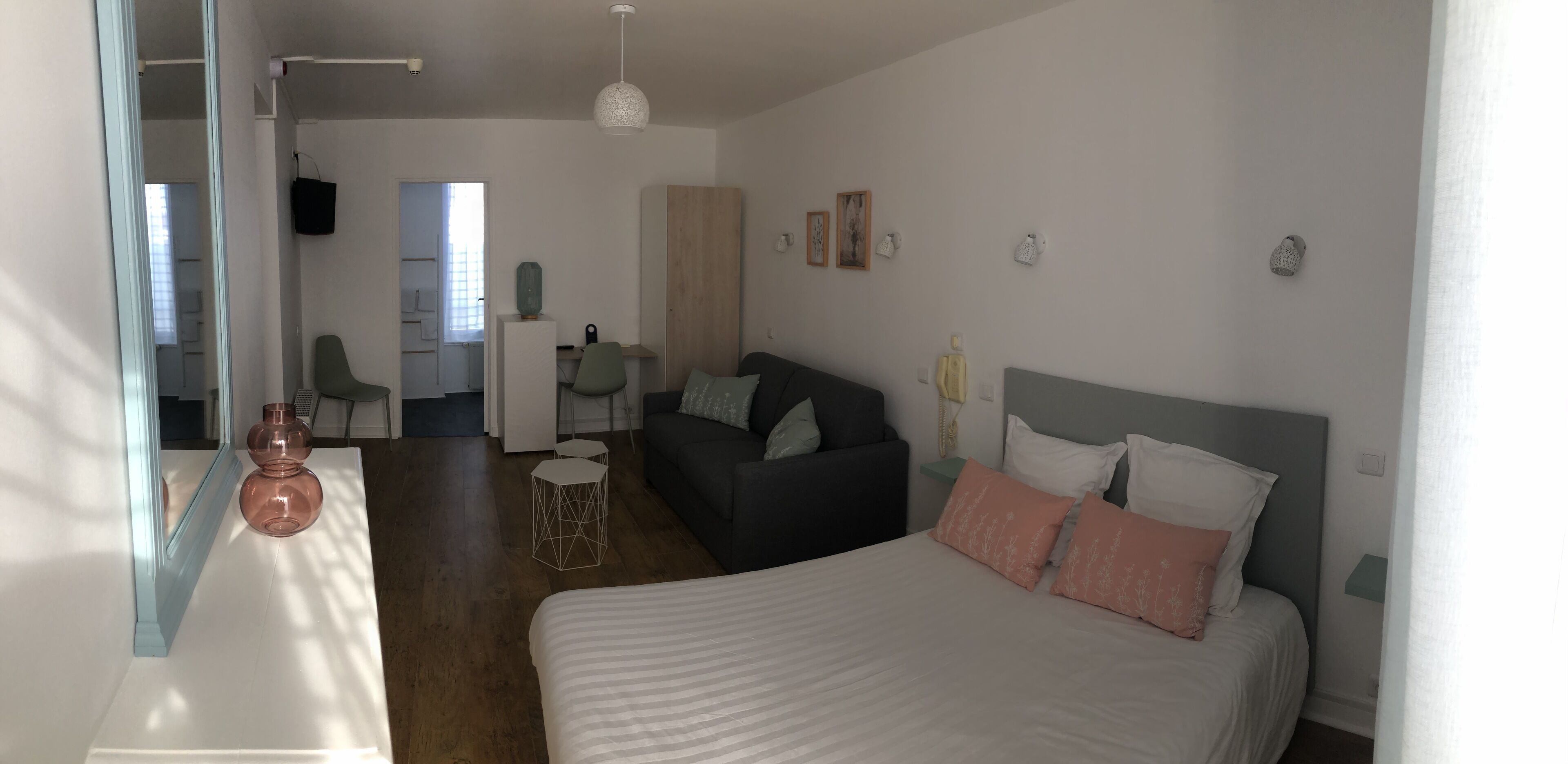 A modern bedroom with a bed, a sofa, a desk, and a chair.