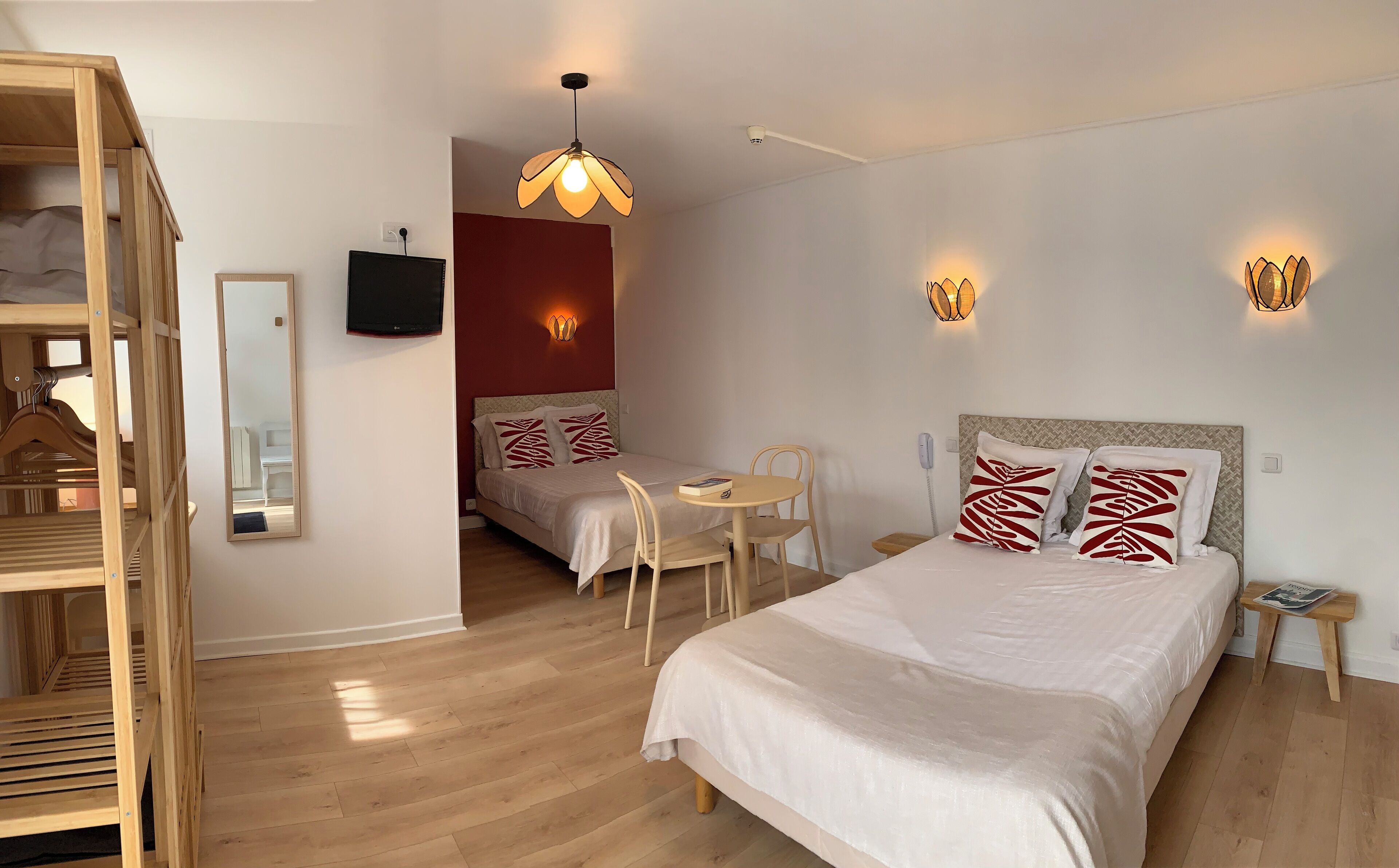 Una habitación de hotel con una cama, una mesita con sillas, un televisor y un espejo.