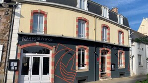A hotel named 'Le Petit France' with a classic European architectural style, featuring a prominent red and black logo, and a sign indicating a hotel. - Hotel de France (Pleneuf-Val-Andre)
