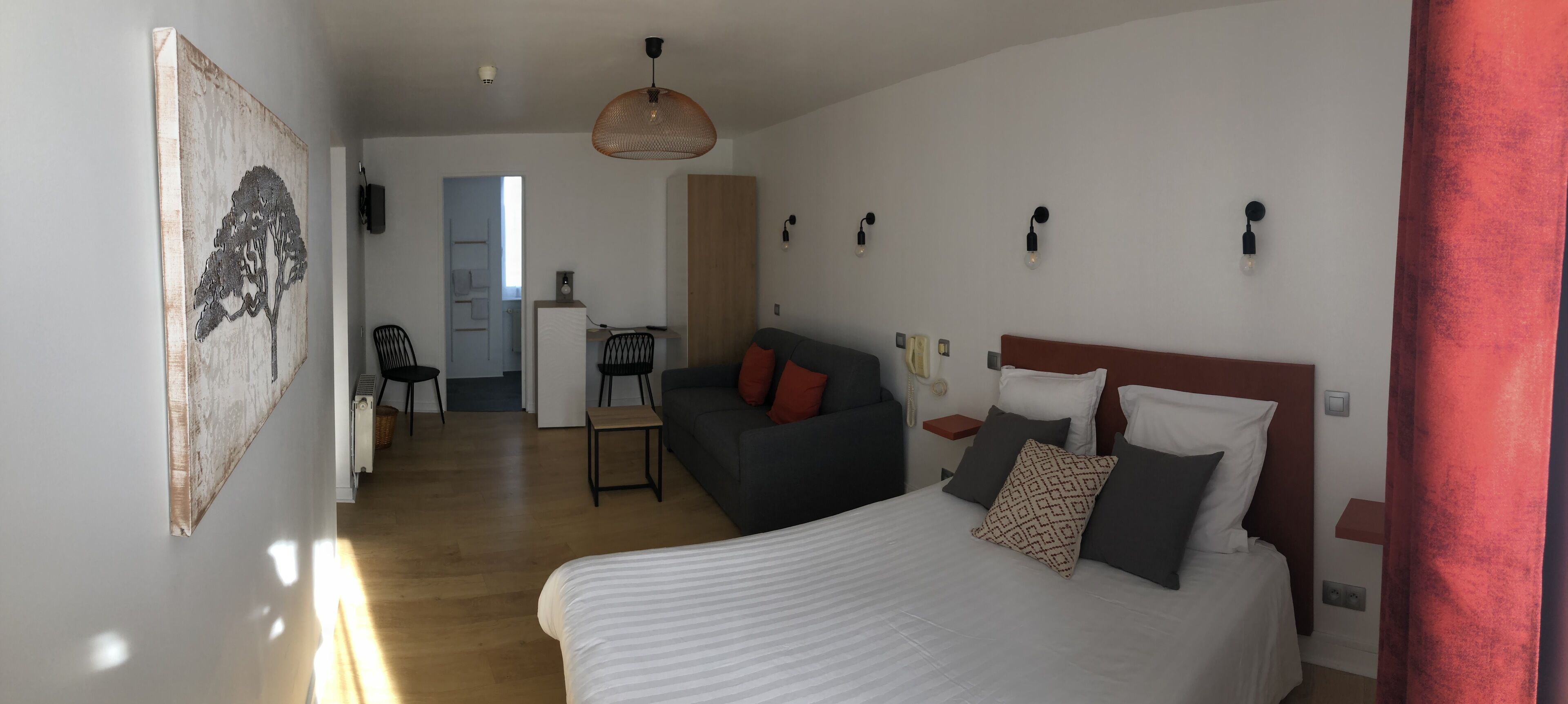 Una camera da letto moderna con un letto grande, una poltrona, una scrivania e un'area pranzo.