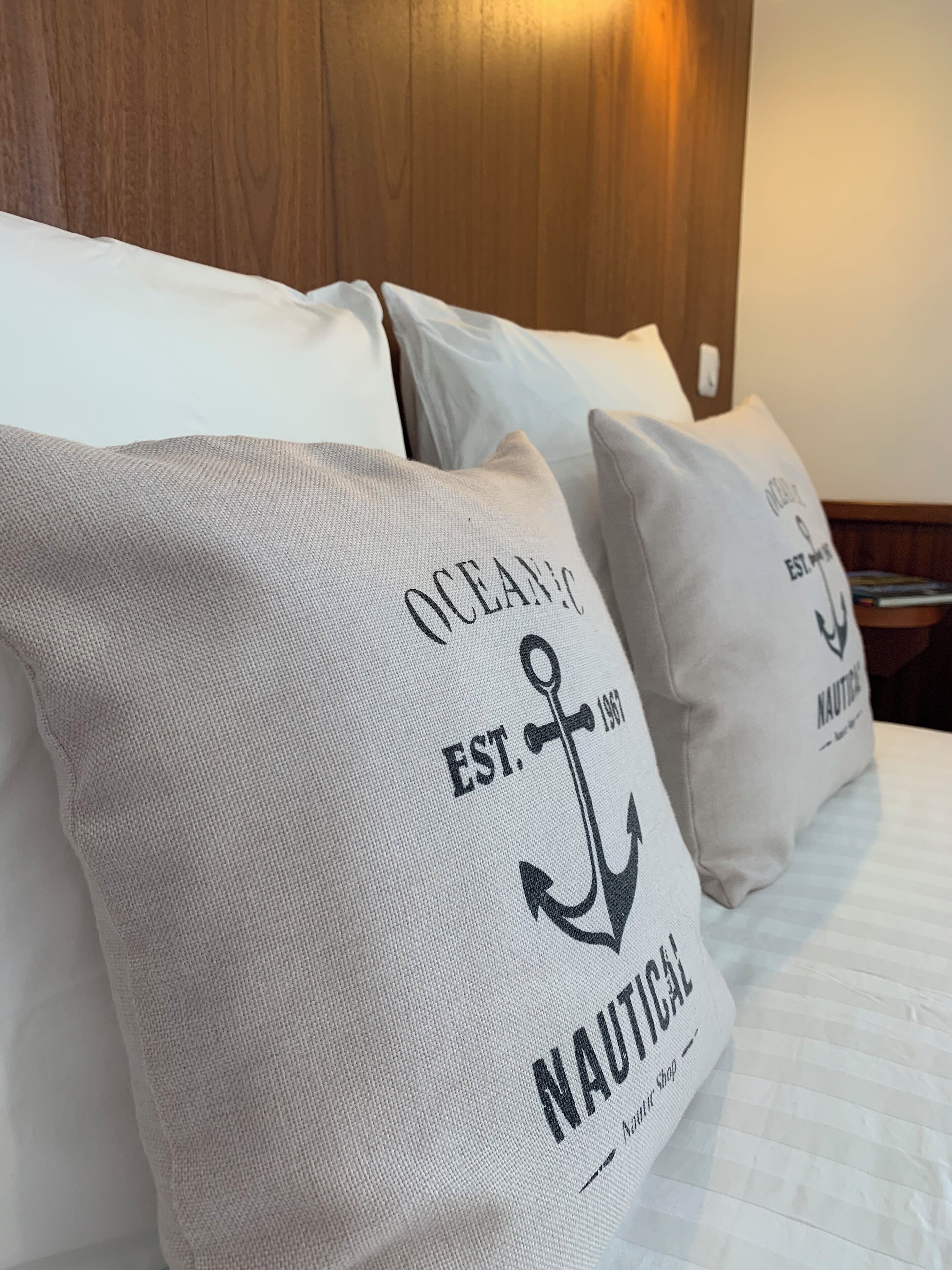 A bed with pillows featuring nautical-themed designs.