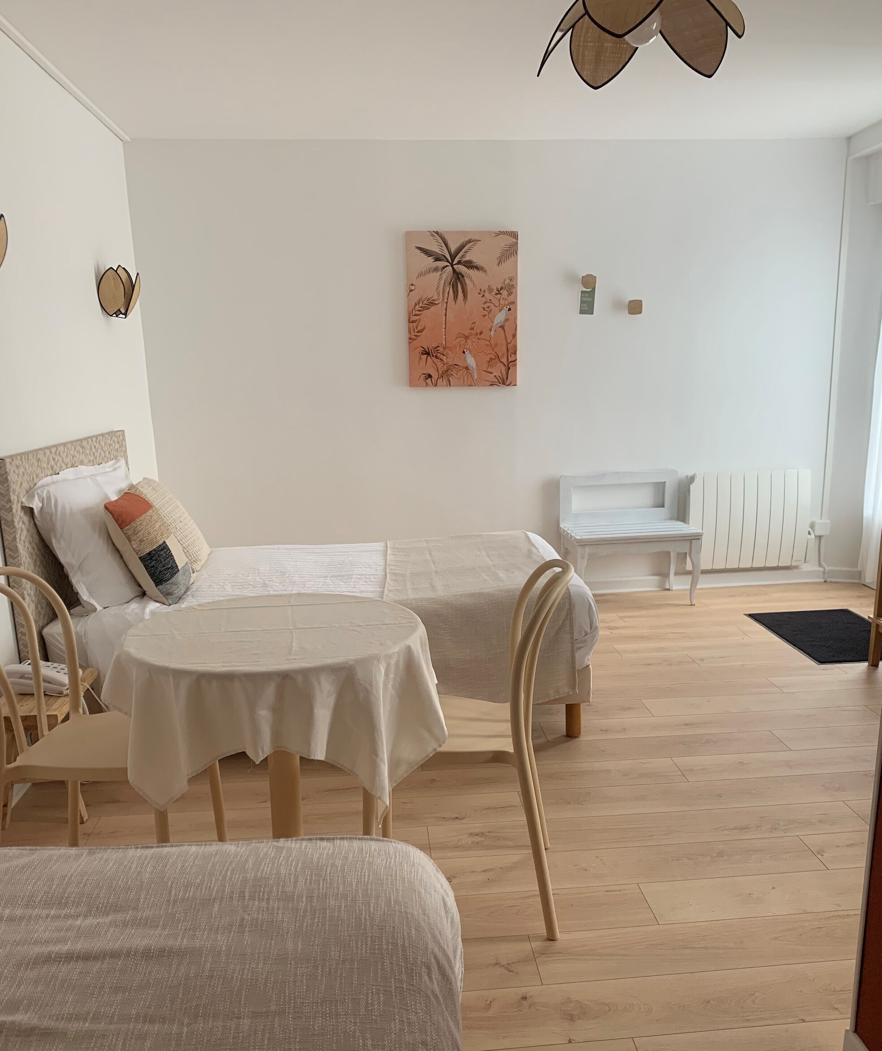 Een kamer met twee bedden, een tafeltje en een stoel. Er hangt een schilderij aan de muur en er is een plafondventilator.