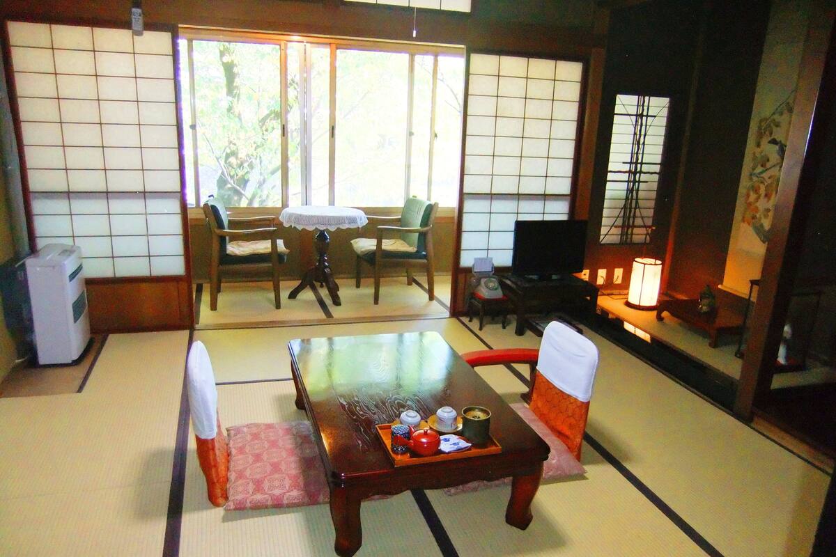 A traditional Japanese room with tatami flooring, a low table with a tray of items, and a television.