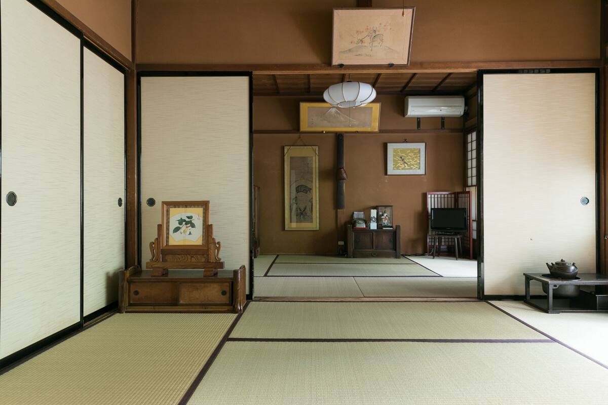 A traditional Japanese room with tatami flooring, sliding doors, a wooden cabinet, and a television.