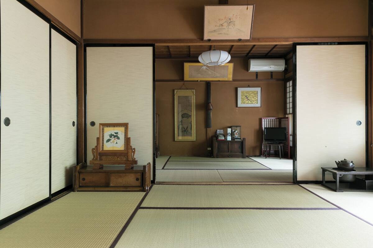 A traditional Japanese room with tatami flooring, sliding doors, a wooden cabinet, and a television.