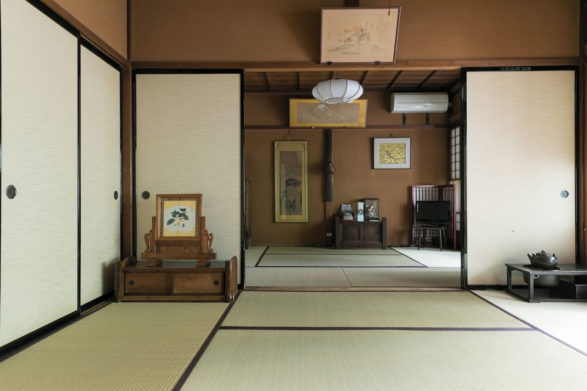 Una habitación japonesa tradicional con suelo de tatami, puertas correderas, un armario de madera y un televisor.