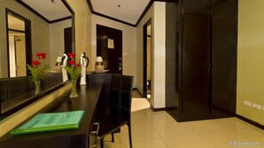A hotel room with a dining area featuring a black table, chairs, and a mirror. There are vases with red flowers on the table. - Richmond Plaza Hotel (Cebu City)