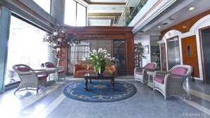 A lobby with wicker chairs, a coffee table with a floral arrangement, and a blue patterned rug. - Richmond Plaza Hotel (Cebu City)
