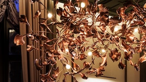 A modern interior with a decorative copper chandelier, a framed artwork on the wall, and a potted plant on a marble surface. - Hotel Sosei Sapporo - MGallery Collection (Sapporo)