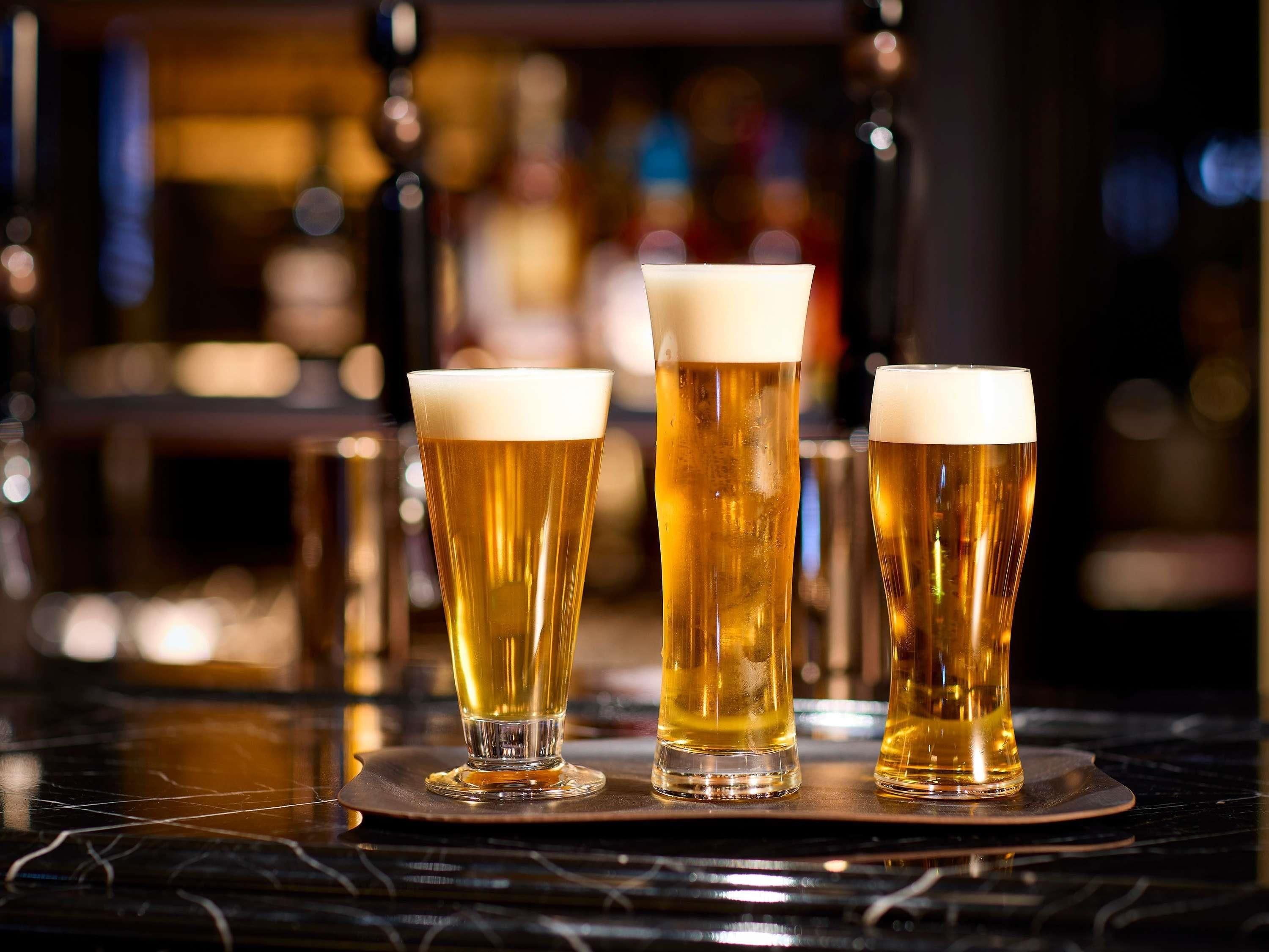 Three glasses of beer on a bar counter.