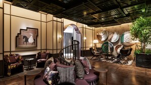 A modern lobby with a curved seating area, a staircase, and a wall decorated with plates and a horse painting. - Hotel Sosei Sapporo - MGallery Collection (Sapporo)