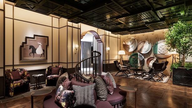 A modern lobby with a curved seating area, a staircase, and a wall decorated with plates and a horse painting. - Hotel Sosei Sapporo - MGallery Collection (Sapporo)