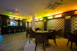 A restaurant with a bar area, multiple tables, and chairs.