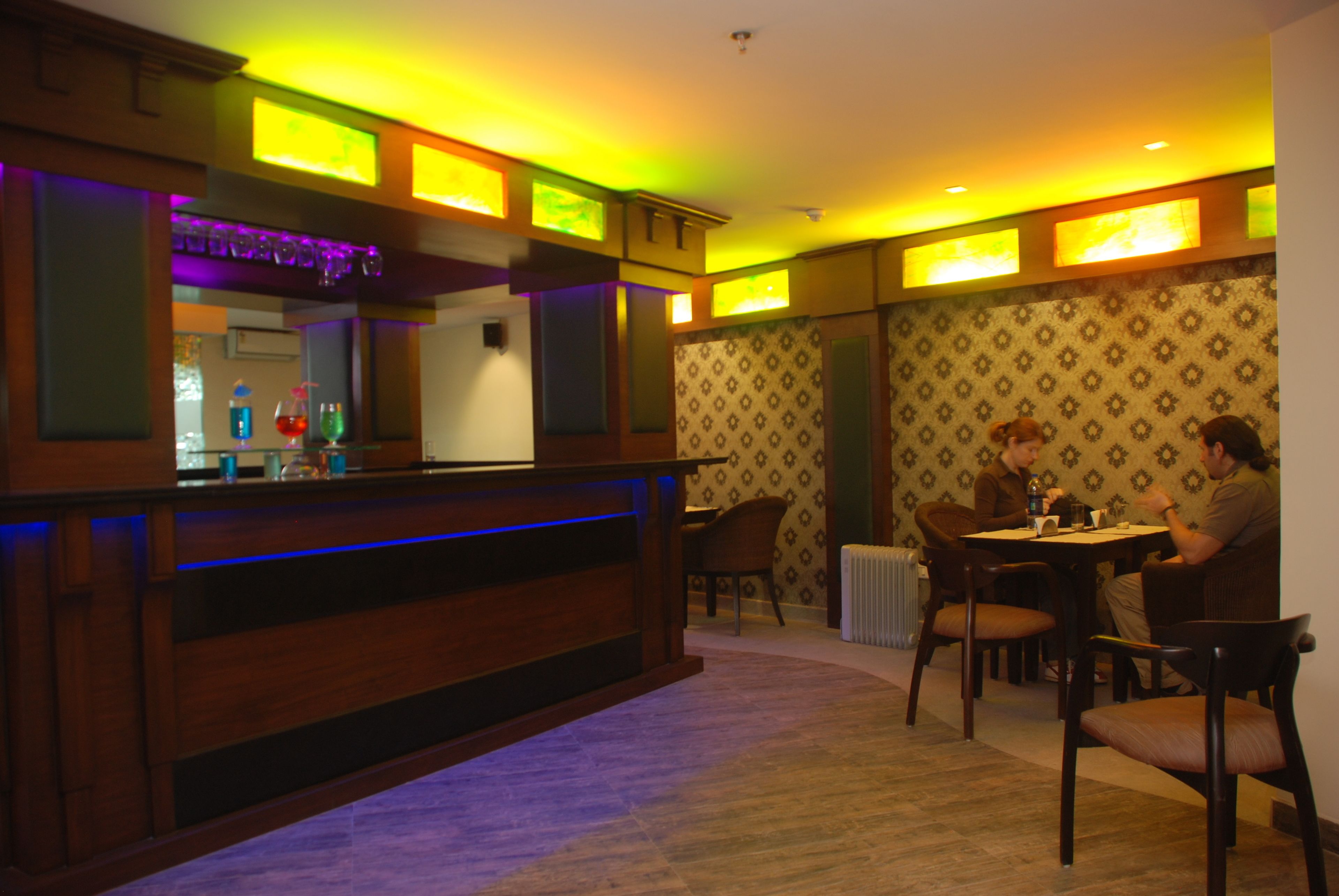 A restaurant with a wooden bar and chairs around a table.