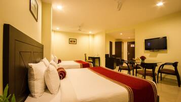 A hotel room with two beds, a desk, a chair, a television, and a ceiling fan.