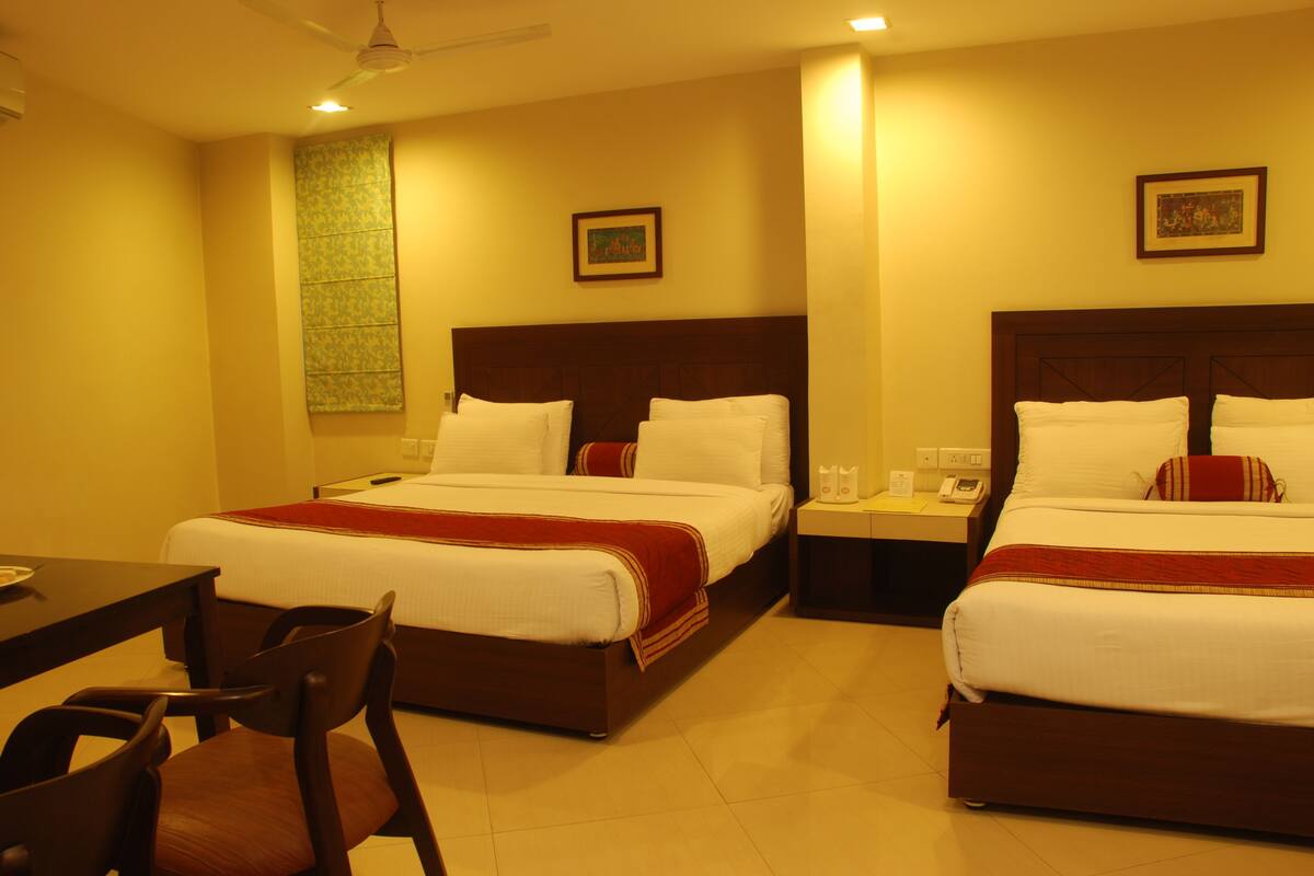 A hotel room with two beds, a desk, and a chair.