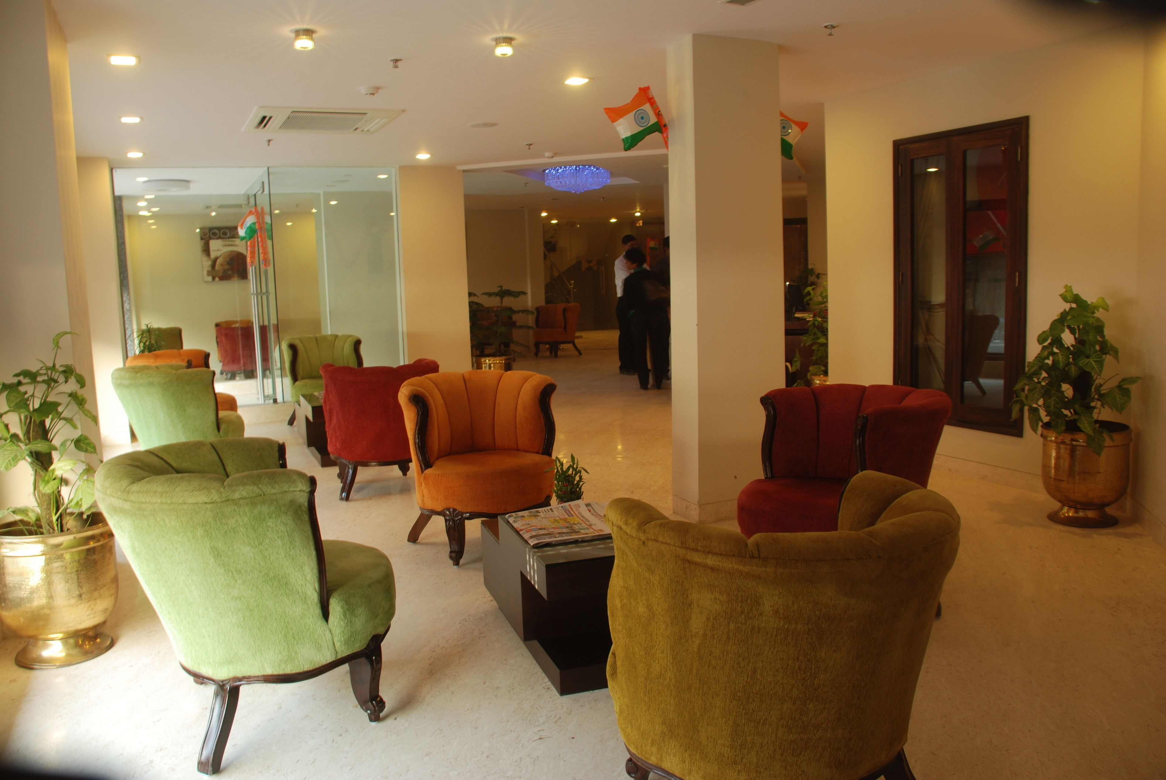 A lobby with multiple armchairs in various colors, a coffee table, and a potted plant.