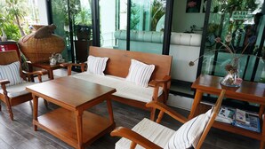 A wooden furniture set with a sofa and chairs, a coffee table, and a side table with books. - Smile Hua-Hin Resort (Hua Hin)
