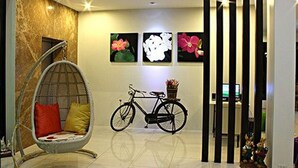 A modern interior with a hanging chair, a bicycle, and three framed floral artworks on the wall. - Smile Hua-Hin Resort (Hua Hin)