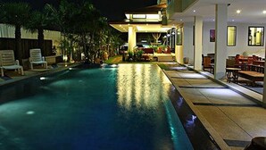 A swimming pool with lounge chairs and a dining area adjacent to it. - Smile Hua-Hin Resort (Hua Hin)
