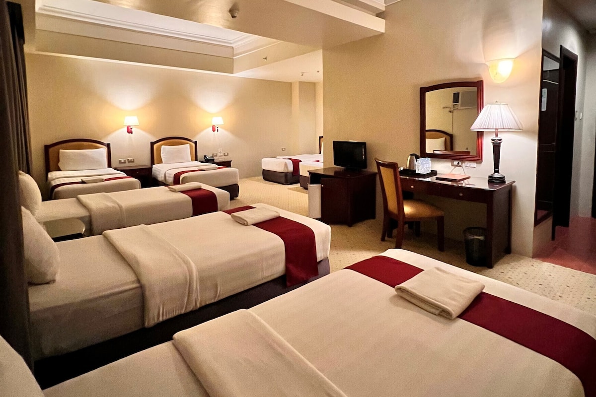Ein Hotelzimmer mit zwei Betten, einem Schreibtisch, einem Sessel, einem Fernseher und einem Spiegel.