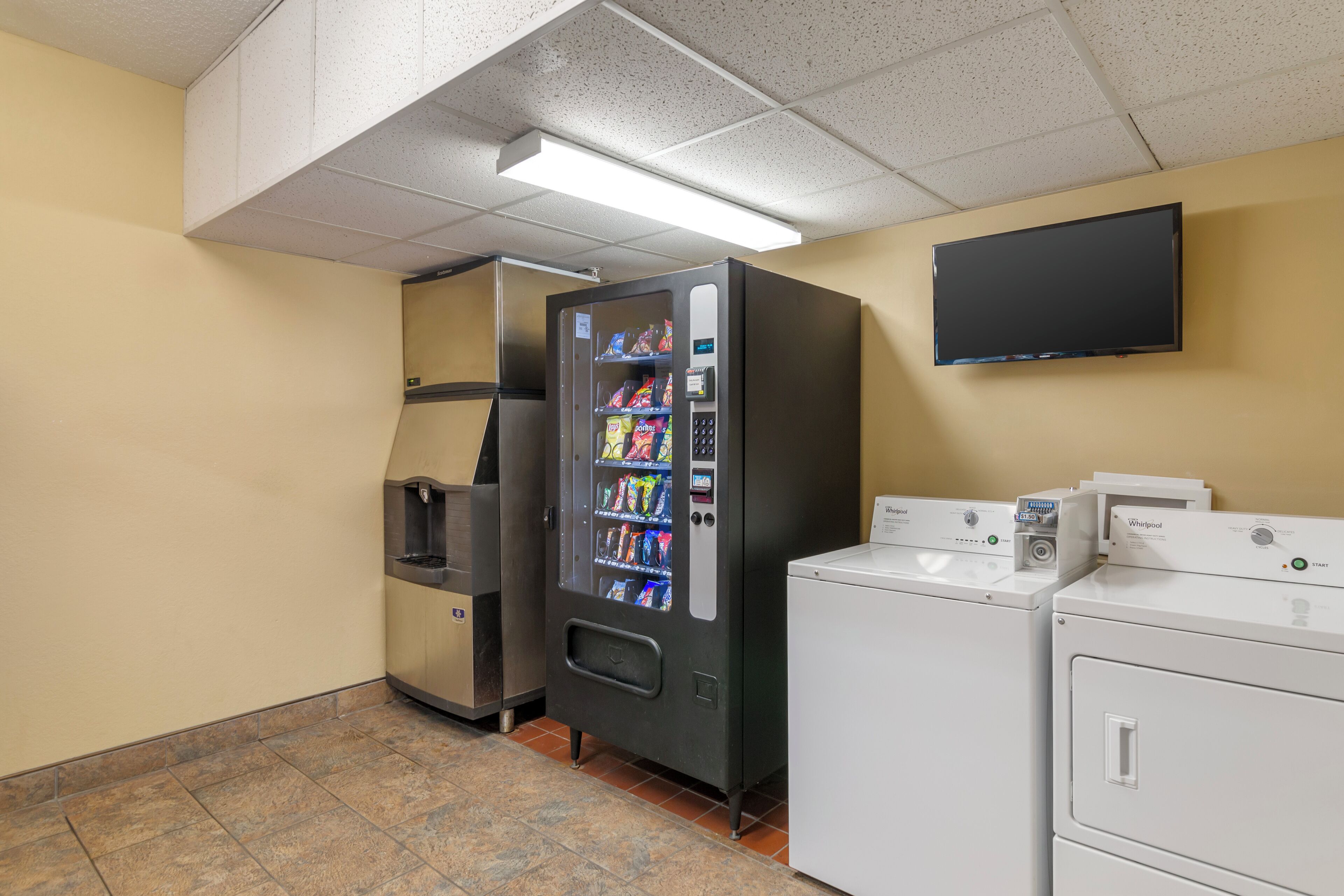 A laundry area with a vending machine, a washer, and a dryer.