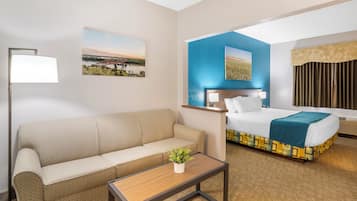 Ett hotellrum med en säng, en soffa, ett soffbord och två tavlor som hänger på väggen.