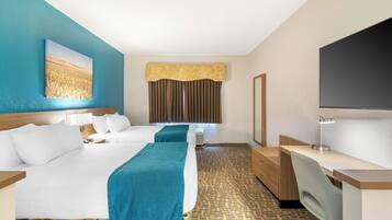 A hotel room with two beds, a desk, a TV, and a large window with curtains.