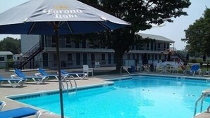 A swimming pool with blue lounge chairs and a Corona Light umbrella. - The Blue Inn At North Fork (East Marion)