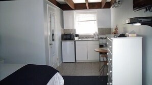 A compact kitchen with white cabinets, a microwave, and a small refrigerator. - The Blue Inn At North Fork (East Marion)