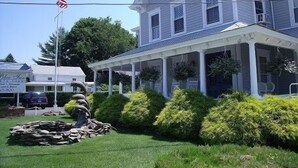 A two-story house with a porch, stone fireplace, and well-maintained landscaping. - The Blue Inn At North Fork (East Marion)