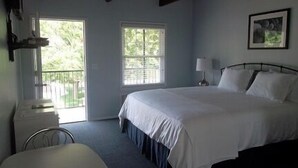 A bedroom with a large bed, a window, a chair, and a lamp. - The Blue Inn At North Fork (East Marion)