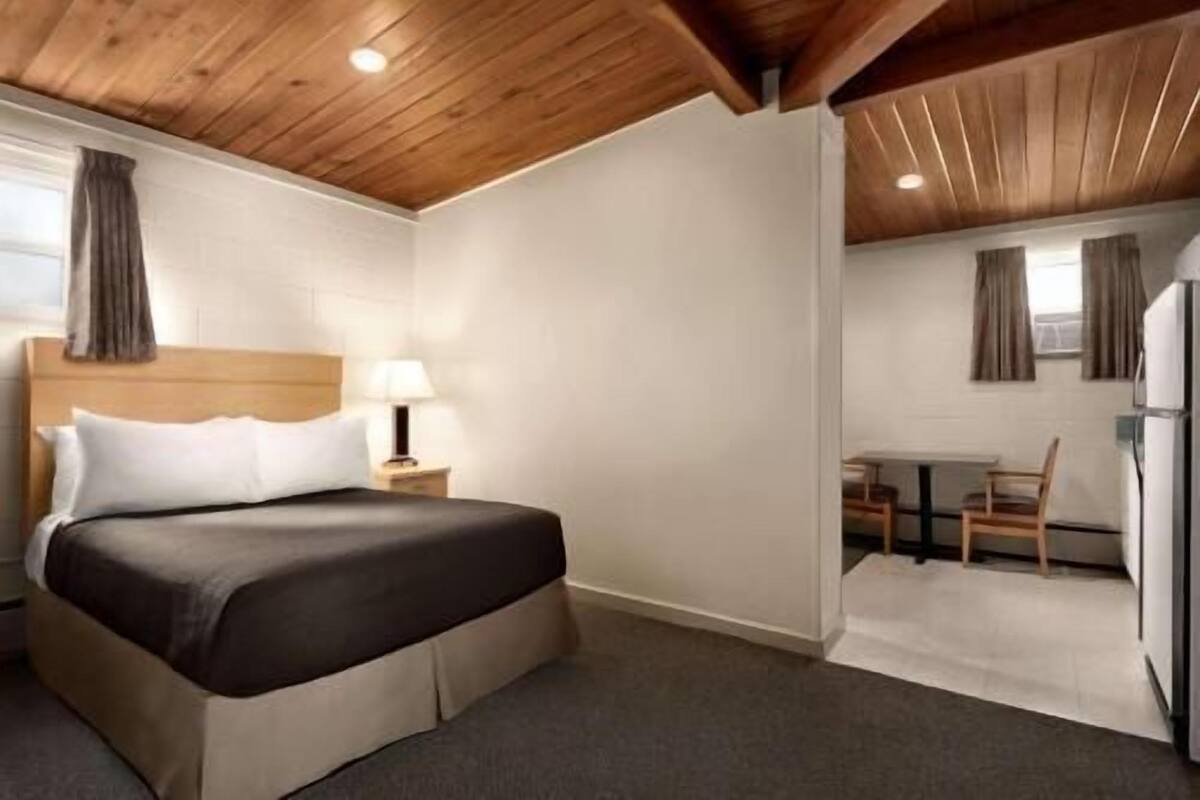 Une chambre d’hôtel avec un lit, une lampe de chevet et une petite table avec des chaises.