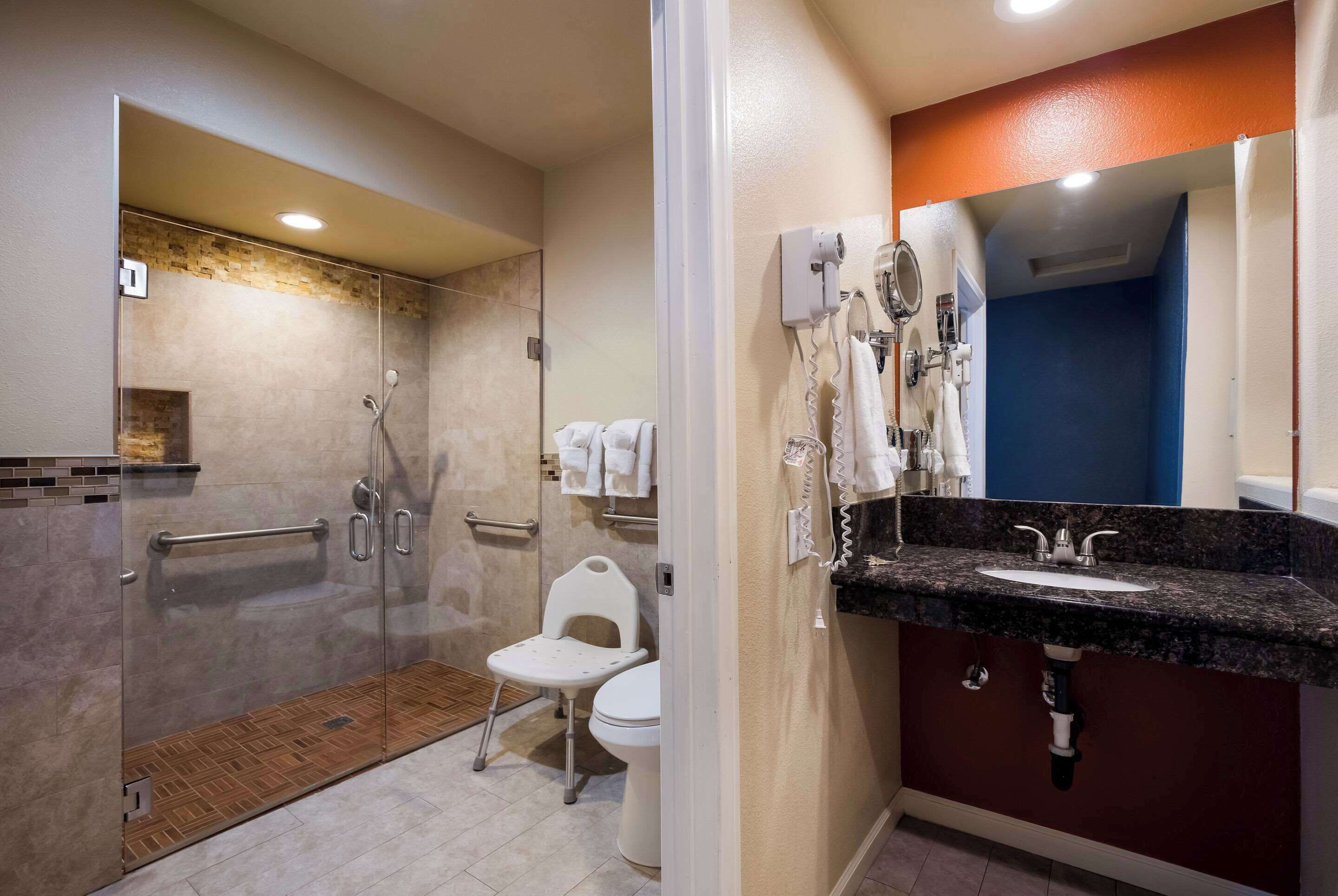 Un baño moderno con cabina de ducha de vidrio, inodoro blanco, tocador con lavamanos y toallero.