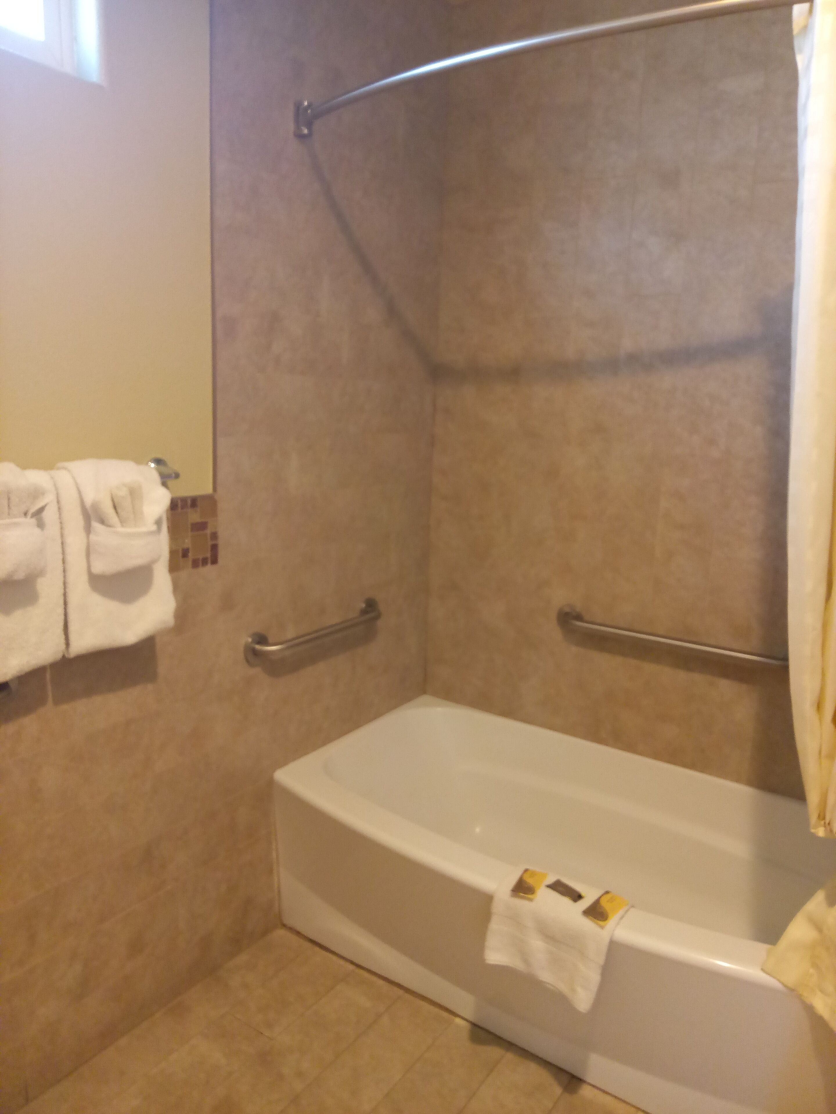 A bathroom with a bathtub, a towel rack, and a shower curtain.