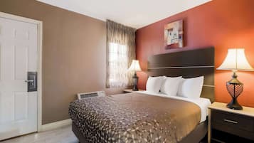 Una camera d'albergo con un letto, due abat-jour, un comodino, una finestra con tende e una porta.