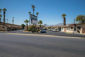 A street view of a motel with a sign reading "RODEWAY INN & SUITES" and several cars parked along the road.