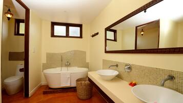 A bathroom with a toilet, a freestanding bathtub, a sink, and a mirror.