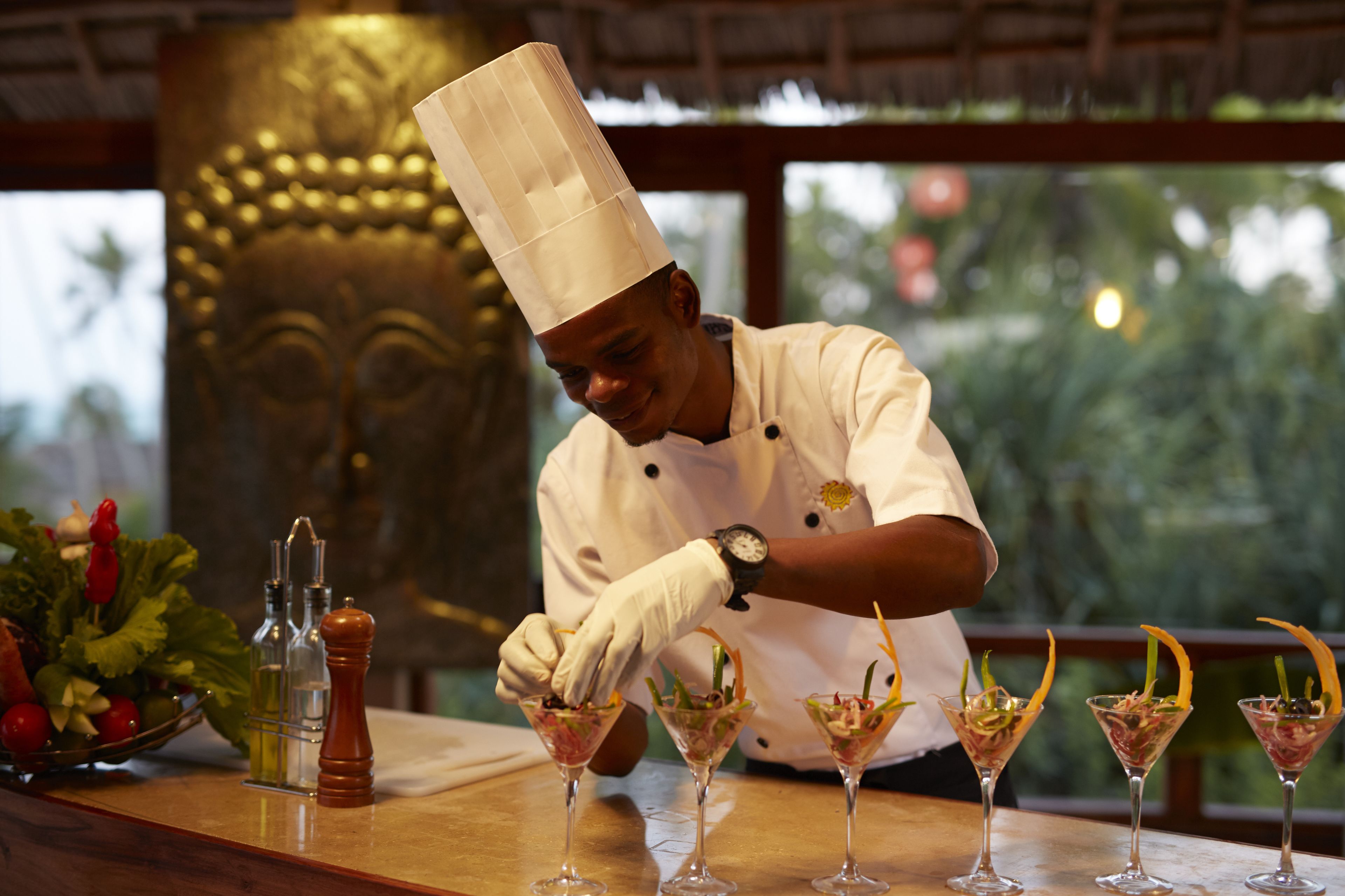 A chef preparing drinks at a bar with a decorative background.