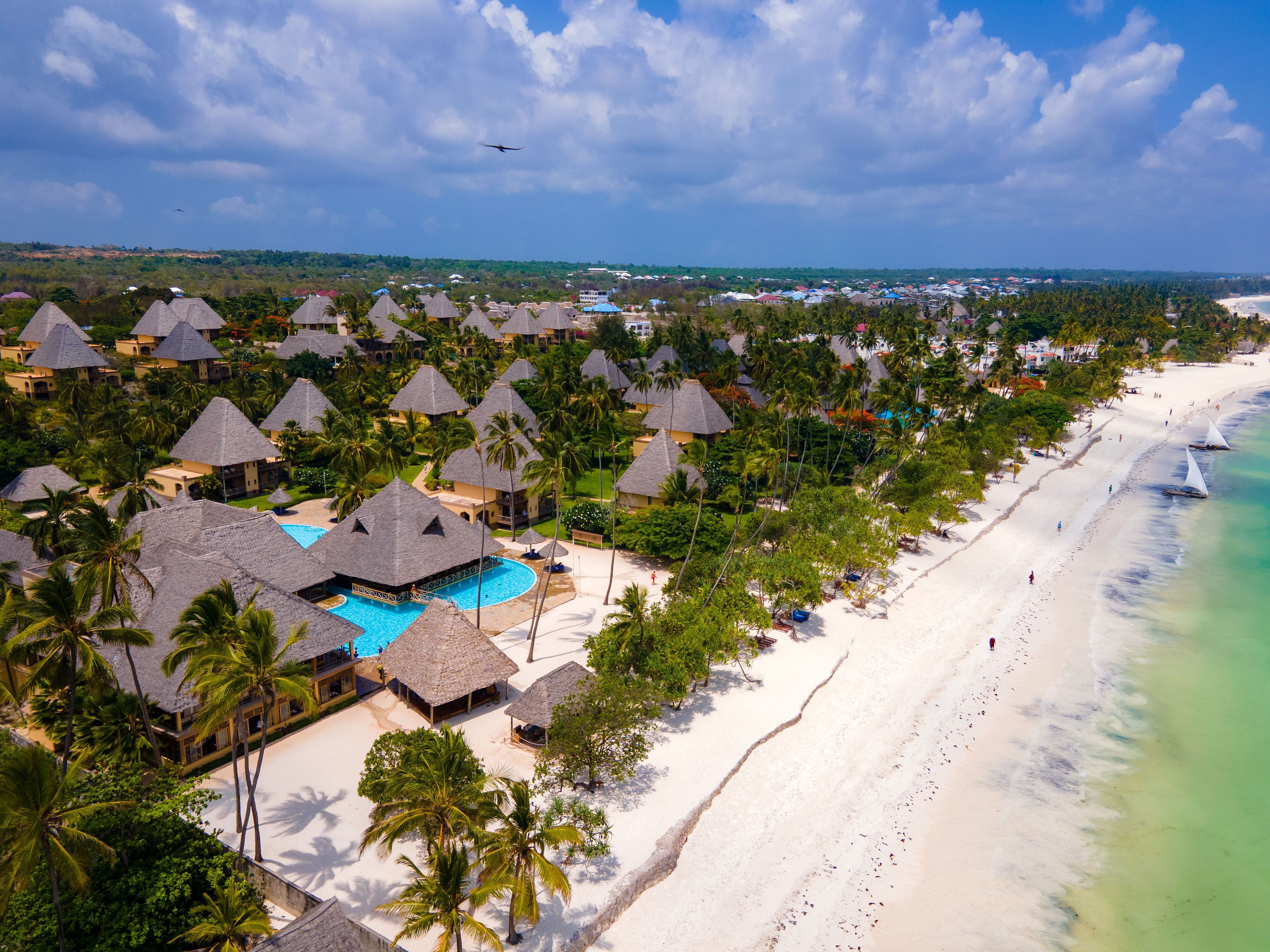 Un complexe hôtelier doté de bungalows aux toits de chaume, d’une piscine et d’une plage.