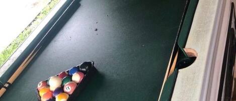 A pool table with a set of billiard balls and a cue stick.