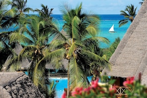 A tropical resort with a pool, palm trees, and a view of the ocean. - Neptune Pwani Beach Resort & Spa Zanzibar (Kiwengwa)