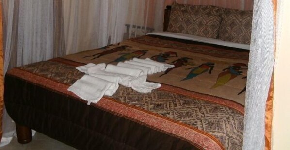 A bed with a patterned bedspread and a neatly folded white towel on it.