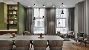 A conference room with a long table, six chairs, and a bookshelf with decorative items. - Residence Inn by Marriott Munich City East (Munich)