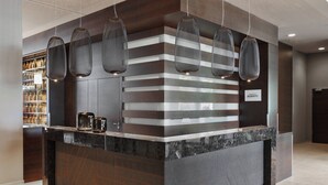 A modern reception desk with a marble top, a dark wood panel, and a sign for Marriott Bonvoy. - Residence Inn by Marriott Munich City East (Munich)